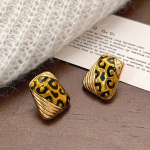 Geometric trapezoid leopard print earrings in gold plating on a wooden surface