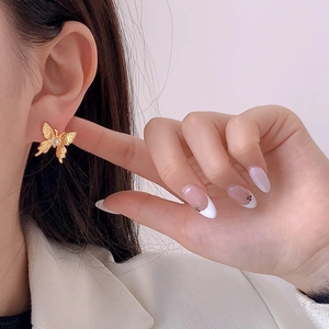 Elegant gold butterfly stud earrings with zircon stone on model's ear earlobe