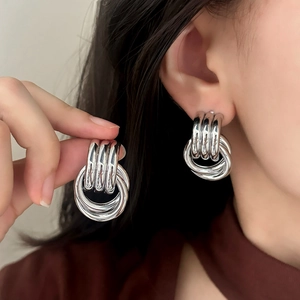 Modern thick geometric silver layered hoop earrings with polished metal finish on model