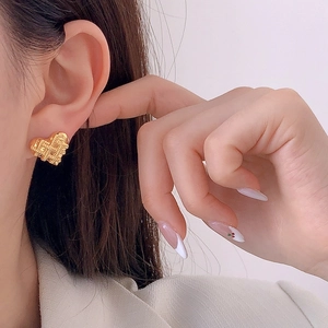 Boucles d'oreilles cœur doré avec texture tressée géométrique sur un mannequin