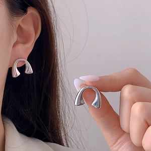 Minimalist silver horseshoe hoop earrings with sleek metallic finish on model