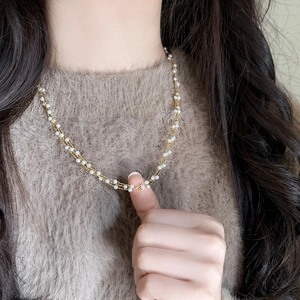 Elegant three-layer pearl necklace with gold plated chain on a model wearing brown sweater