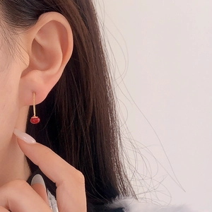 Elegant red pearl drop earrings with long gold chain tassel shown on a model's ear