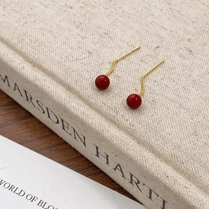 Retro Ancora red pearl tassel earrings with gold plating on a textured vintage book