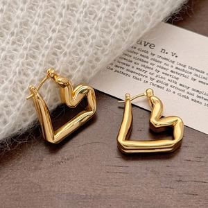 Elegant gold heart-shaped earrings with liquid metal texture on white knit background