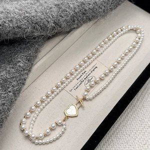 Detail of double-layer pearl necklace with golden heart-shaped OT toggle clasp