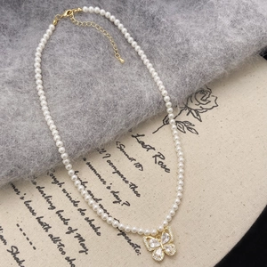 Gros plan d'un collier de perles avec pendentif nœud doré serti de micro-zirconiums