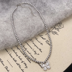 Détail du collier de perles grises avec pendentif nœud serti de zircons brillants