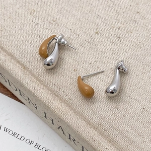 Detailed close-up of water drop earrings in silver polish and ginger glaze on linen
