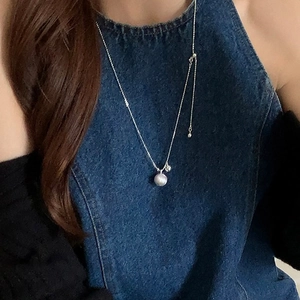 Close-up of adjustable silver chain necklace with pearl pendant worn by model
