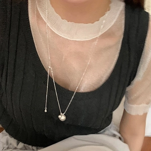 Close-up of a silver adjustable Y-necklace with solid ball pendants on a model