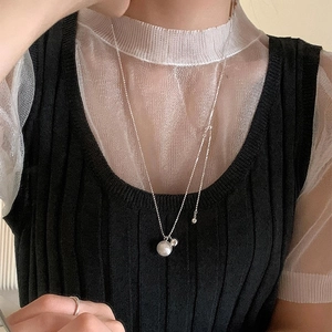 Detail of silver long adjustable necklace with minimalist sphere pendant worn by a model