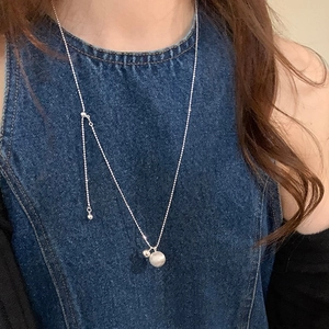Detail of adjustable silver necklace with matte and polished dual beads on denim