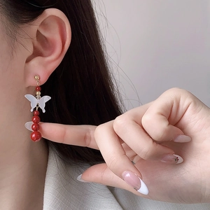 Elegant butterfly earrings with mother-of-pearl and red pearls shown on a model