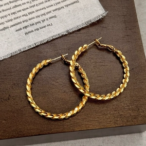 Vintage golden twisted hoop earrings with elegant metal texture on dark wood background