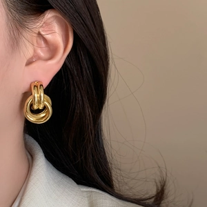 Chic multi-layered geometric interlocking gold hoop earrings shown on a female model