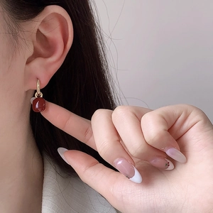 Eleganti orecchini a cerchio dorati con ciondoli quadrati in resina rossa indossati da modella