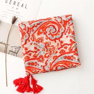Dettaglio della sciarpa rossa paisley con lunghe frange e consistenza in lino