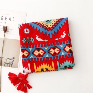 Détail d'une écharpe bohème rouge avec motifs ethniques et pompons rouges élégants