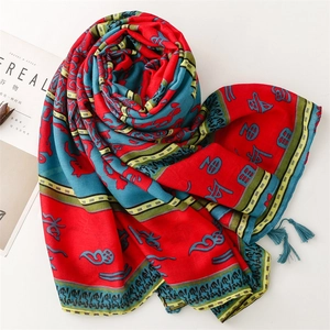Detail of ethnic totem scarf featuring red and blue patterns with soft fringe edges
