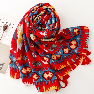 Gros plan d'une écharpe bohème rouge avec motifs géométriques et pompons assortis