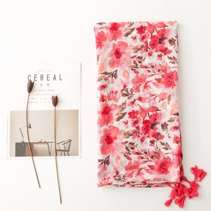 Detail of floral cotton linen scarf with red fringe tassels and artistic flower patterns