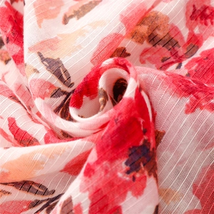 Close-up of red floral cotton-linen scarf fabric showing fine texture and tassels