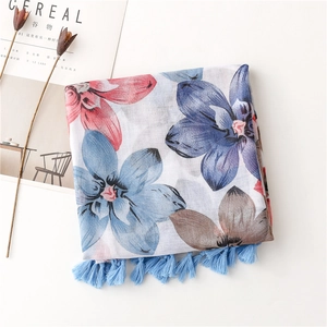 Détail d'une écharpe en coton-lin avec imprimé floral et glands bleu céleste