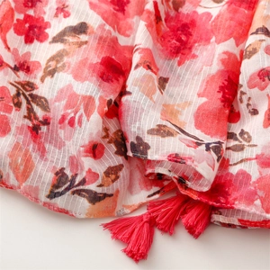 Macro detail of red floral print cotton-linen scarf with textured weave and fringe trim