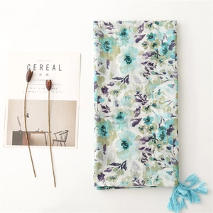 Close-up of floral linen scarf featuring light blue tassels and watercolor flower prints