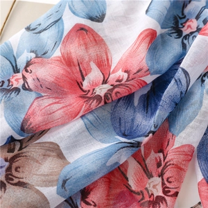Détail d'une écharpe effet lin avec imprimés fleurs rouges et bleues et franges