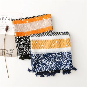 Detail of bohemian scarf with tassels and metallic foil patterns on soft cotton fabric