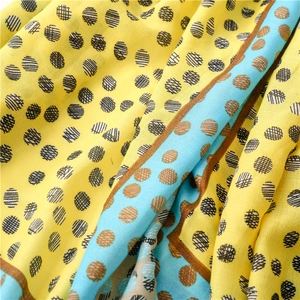Detail view of yellow and blue polka dot scarf showing lightweight fabric and texture