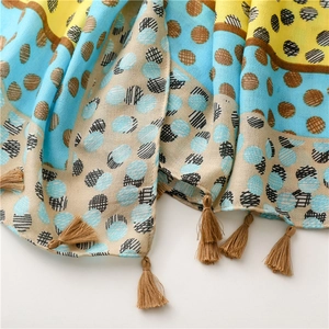 Detail of yellow and blue polka dot scarf showing woven texture and fringe tassels