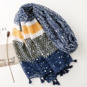 Close-up of bohemian printed scarf with ethnic patterns, silver foil, and navy tassels