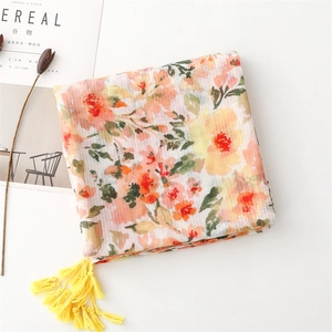 Detail of floral print scarf with soft texture and long yellow fringe tassels on the edge