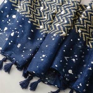 Detailed close-up of dark blue scarf with golden wave patterns and fringe tassels