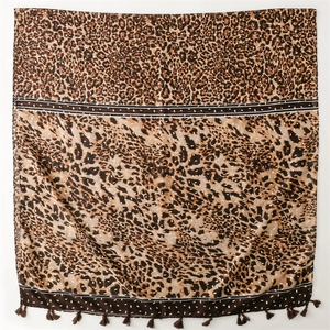 Détail d'une écharpe léopard avec des glands marrons sur un tissu en mousseline légère