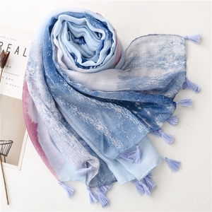 Detail of blue and white gradient scarf featuring fine tassels and soft cotton texture