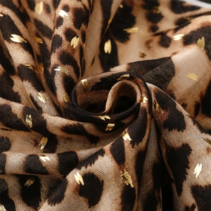 Détail macro d'une écharpe léopard avec accents dorés et texture de tissu tissé