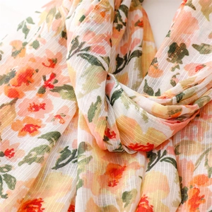 Detailed macro view of floral cotton linen feel scarf with orange blooms and fringe