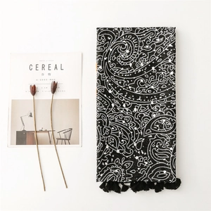 Detail view of paisley pattern scarf with black tassels on minimalist magazine layout