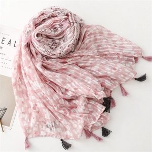 Macro detail of soft cotton-linen scarf featuring pink floral prints and fringe tassels