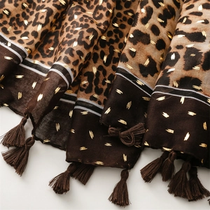 Détail d'écharpe léopard avec accents dorés et décorations de pompons à franges