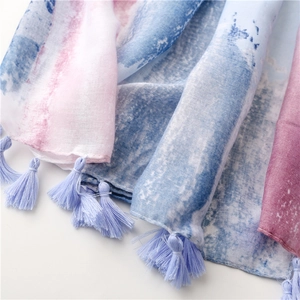 Macro detail of soft gradient pashmina fabric with delicate blue tassel fringes