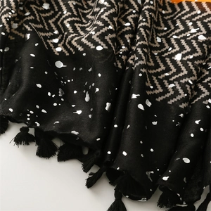 Detail of black scarf featuring silver foil splatters and geometric patterns with fringe