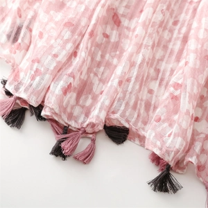 Close-up of pink floral linen scarf with fringe tassels and soft textured fabric