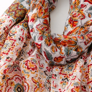 Gros plan du motif mandala floral bohème sur une écharpe légère rouge et orange