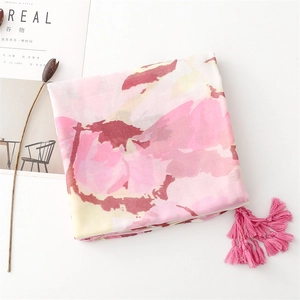 Detail of pink floral scarf with tassels and magazine prop on a minimalist white background