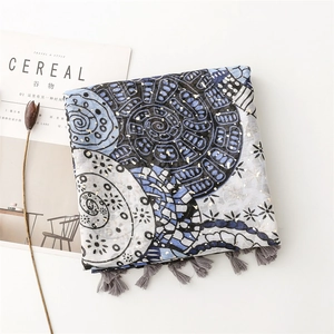 Detail of summer scarf showing blue circular patterns, gold foil accents and tassel edges
